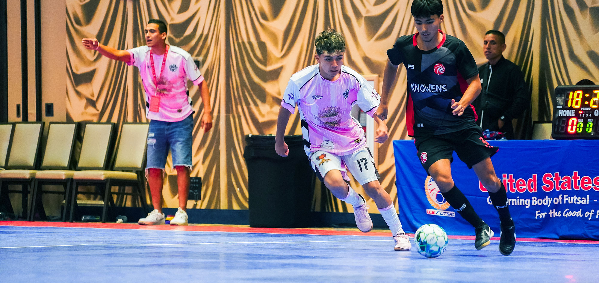 Two boy futsal players chasing the game ball