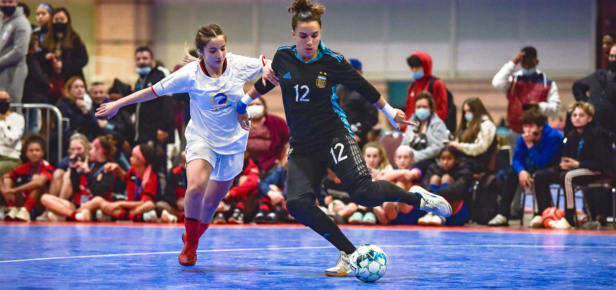 Two women futsal players chasing ball